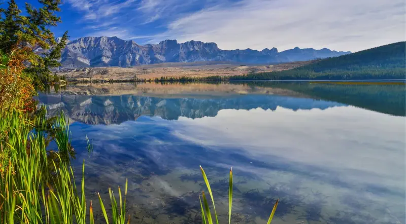 Mountains mirrored in a calm Jasper lake at morning