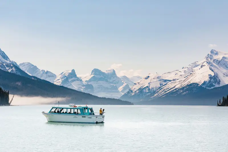 Maligne Lake cruise boat on calm turquoise water below snow-dusted peaks