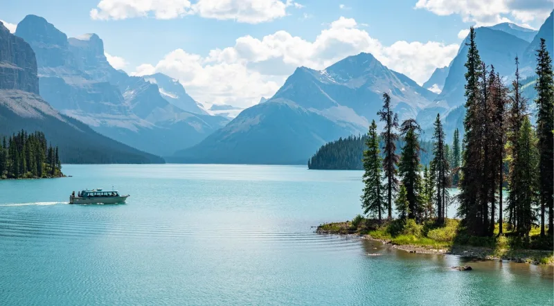 The Maligne Lake cruise boat sailing toward the glaciated peaks of the Hall of the Gods